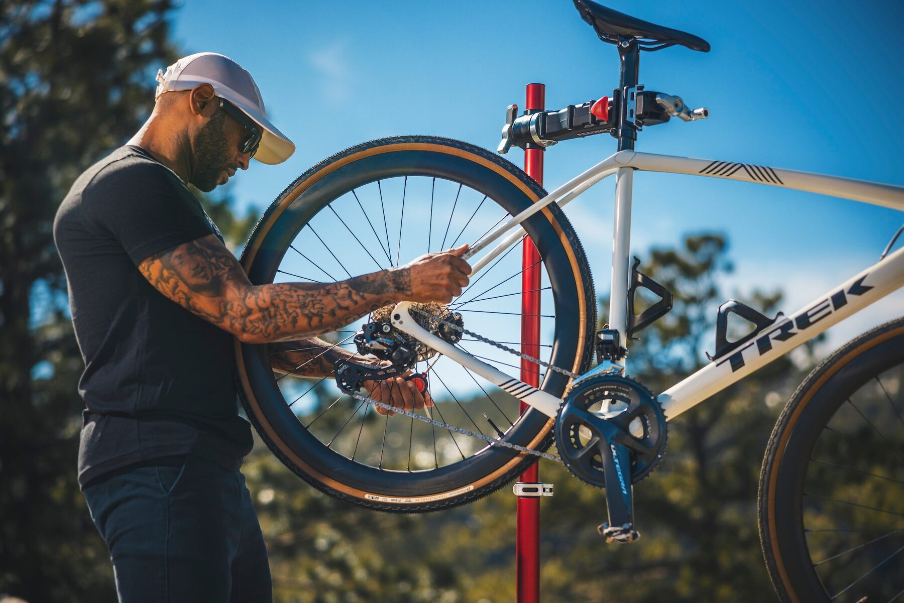 A man repairing a bicycle mounted on a repair stand outdoors