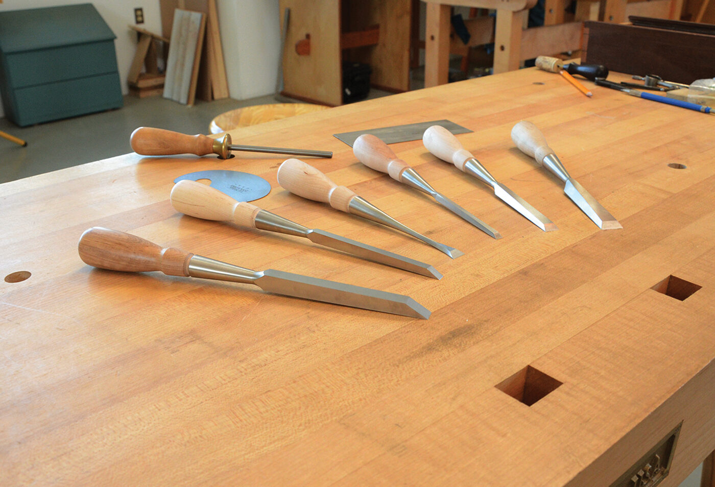 Well-worn hand tools laid out in order on a wooden workbench