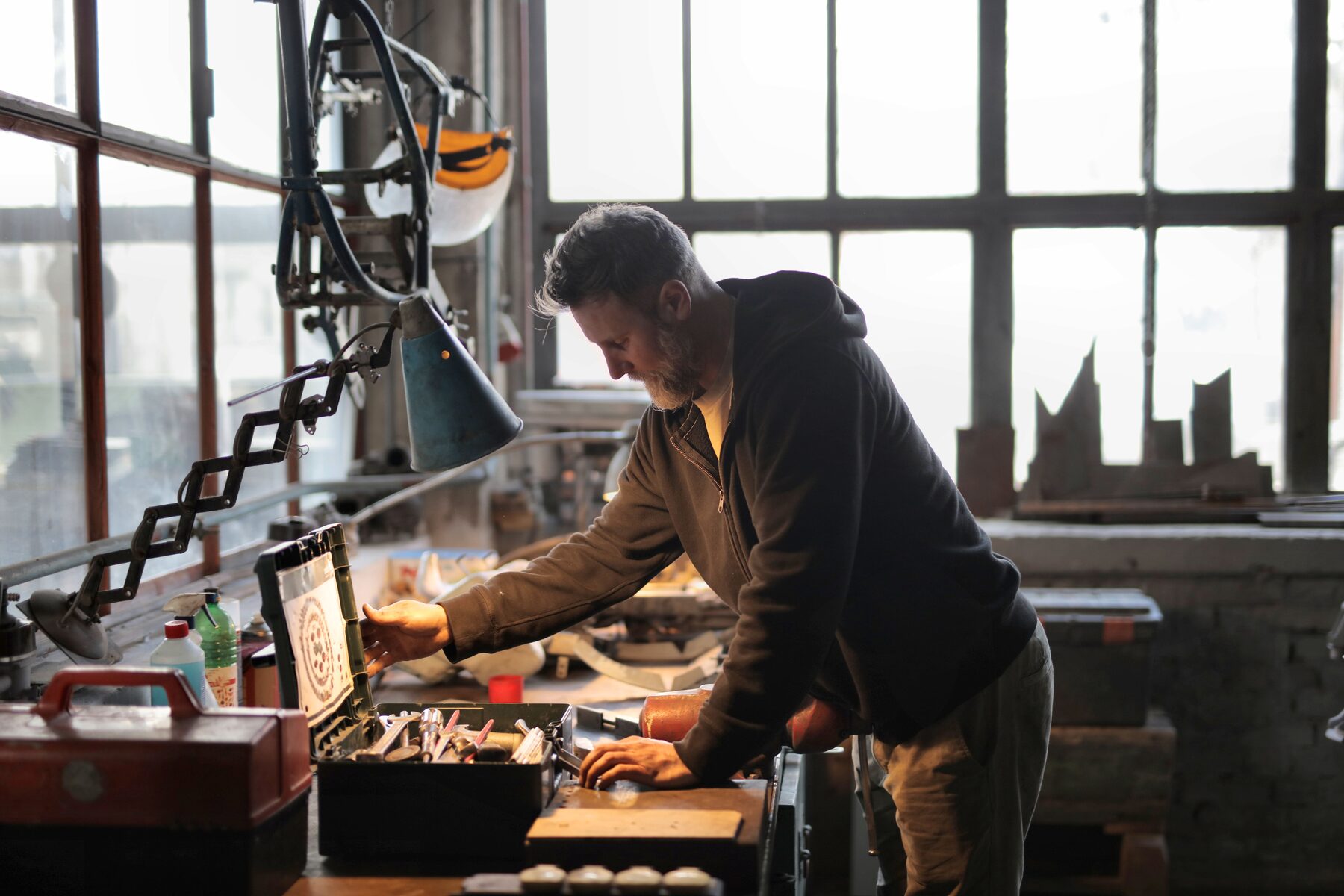 A man at his workbench in a home workshop, tools racked on the wall behind him